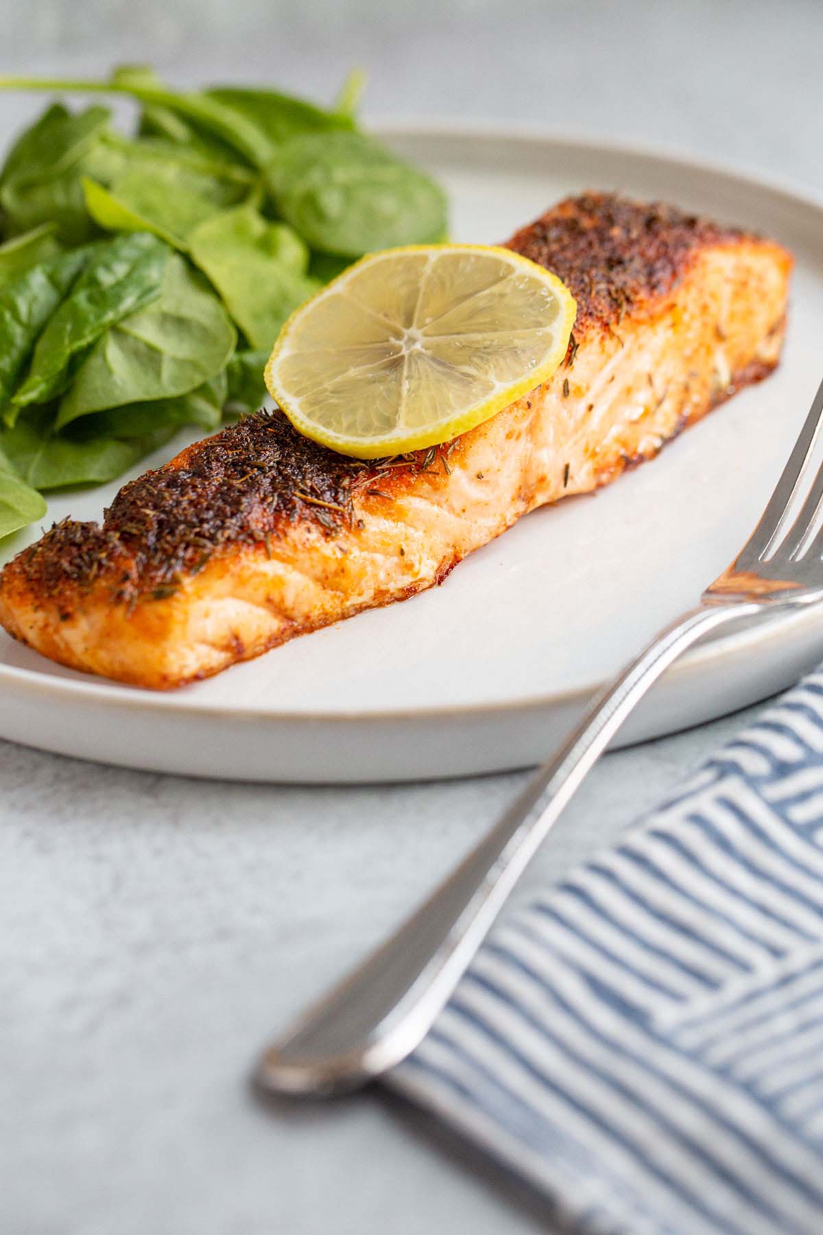 Air fried salmon on a plate with a lemon slice.