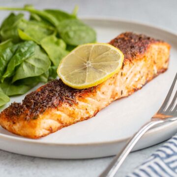 Air fried salmon on a plate with a lemon slice.
