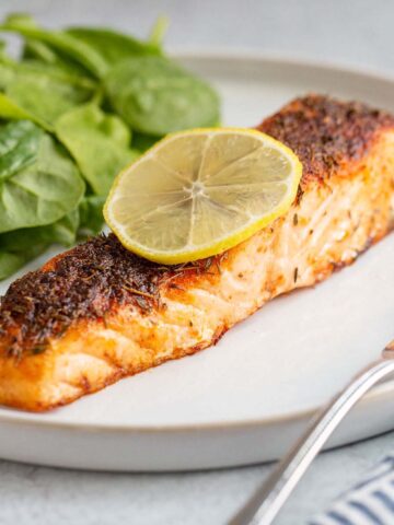 Air fried salmon on a plate with a lemon slice.
