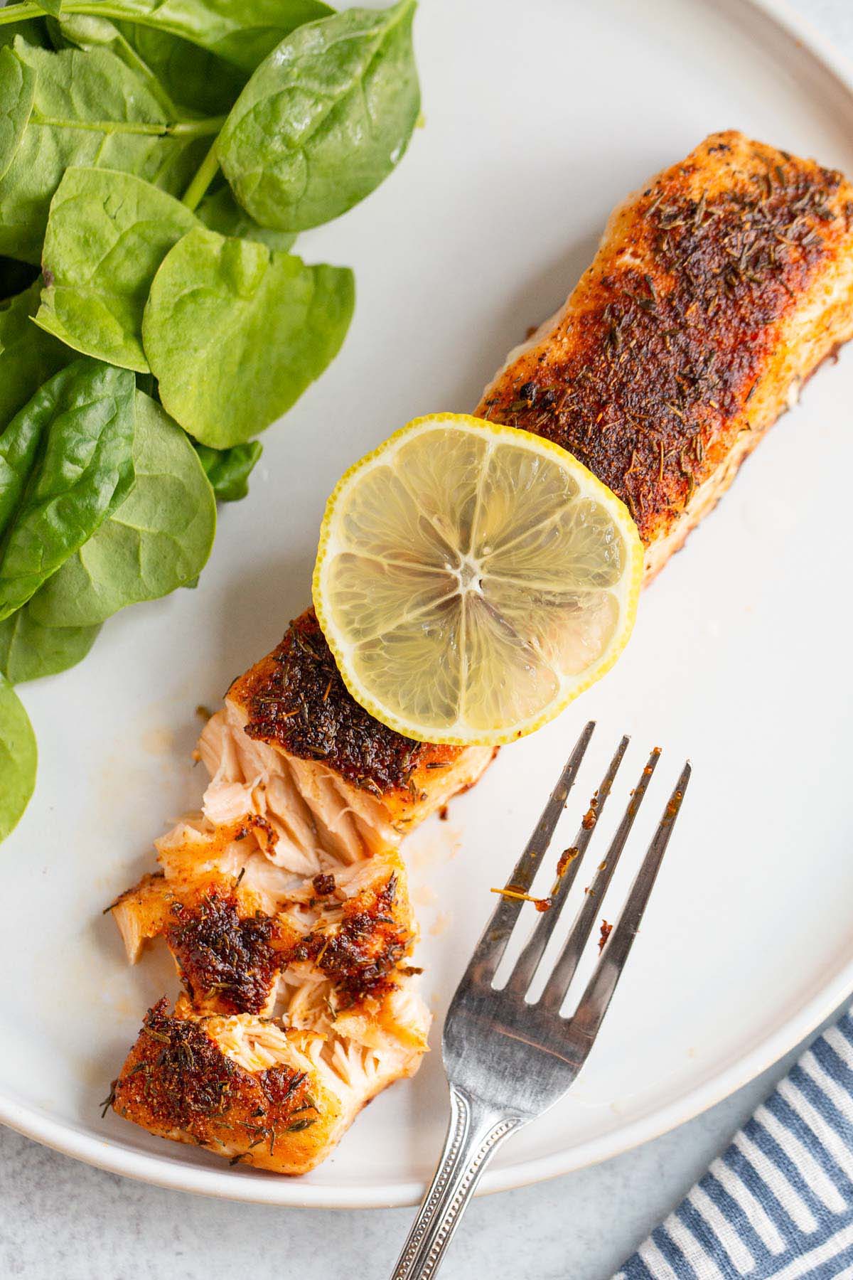 Air fried salmon on a plate with a lemon slice.