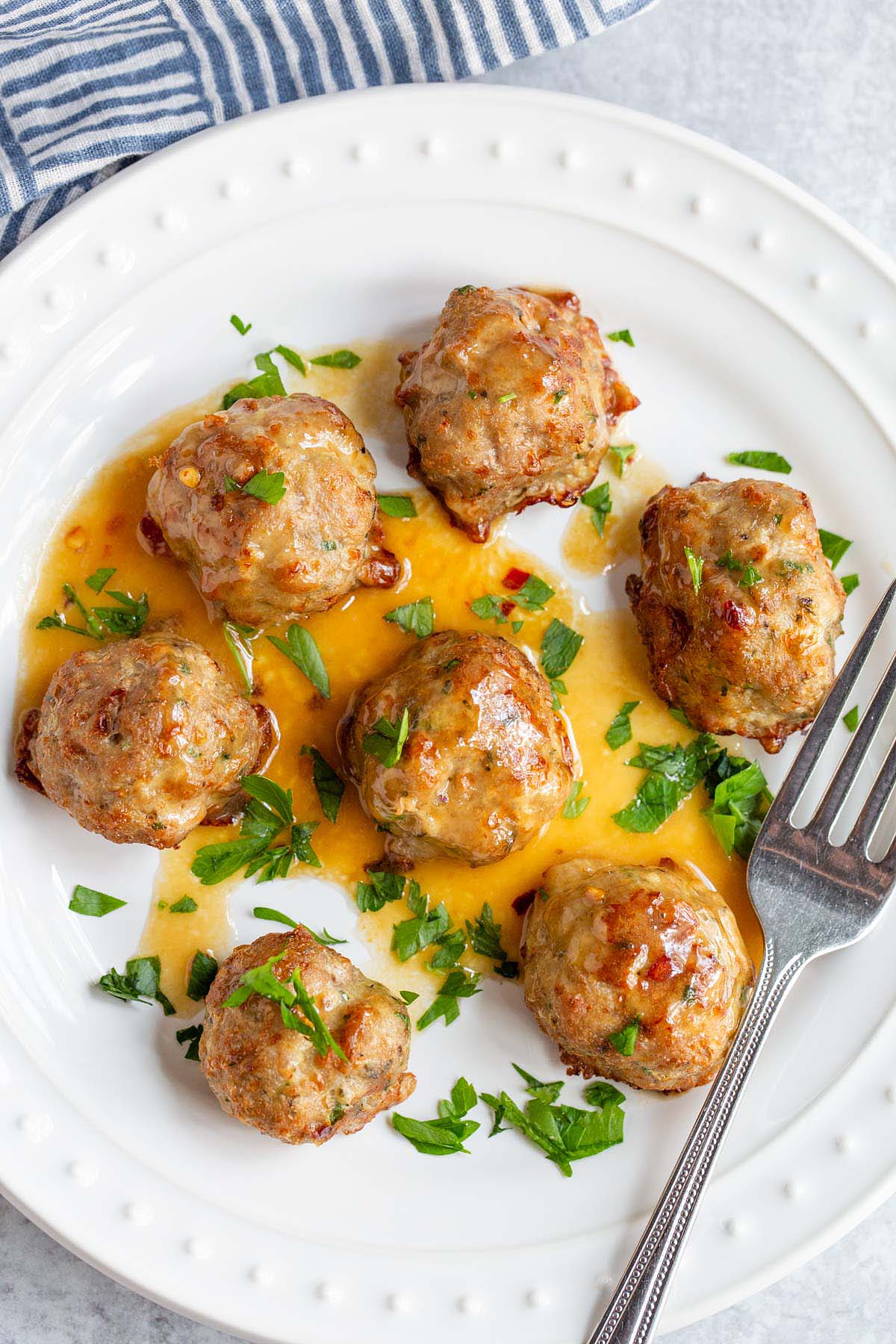 Air fried turkey meatballs with parsley on a white plate.