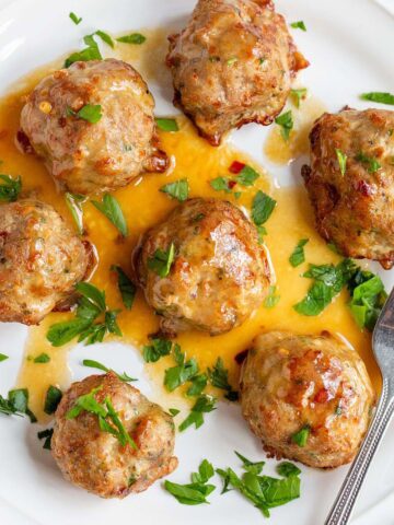 Air fried turkey meatballs with parsley on a white plate.