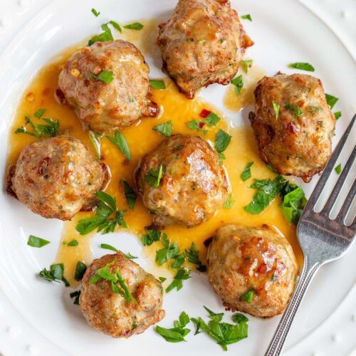Air fried turkey meatballs with parsley on a white plate.