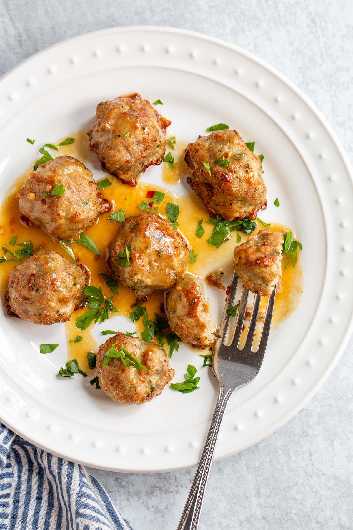 Air fried turkey meatballs with parsley on a white plate.