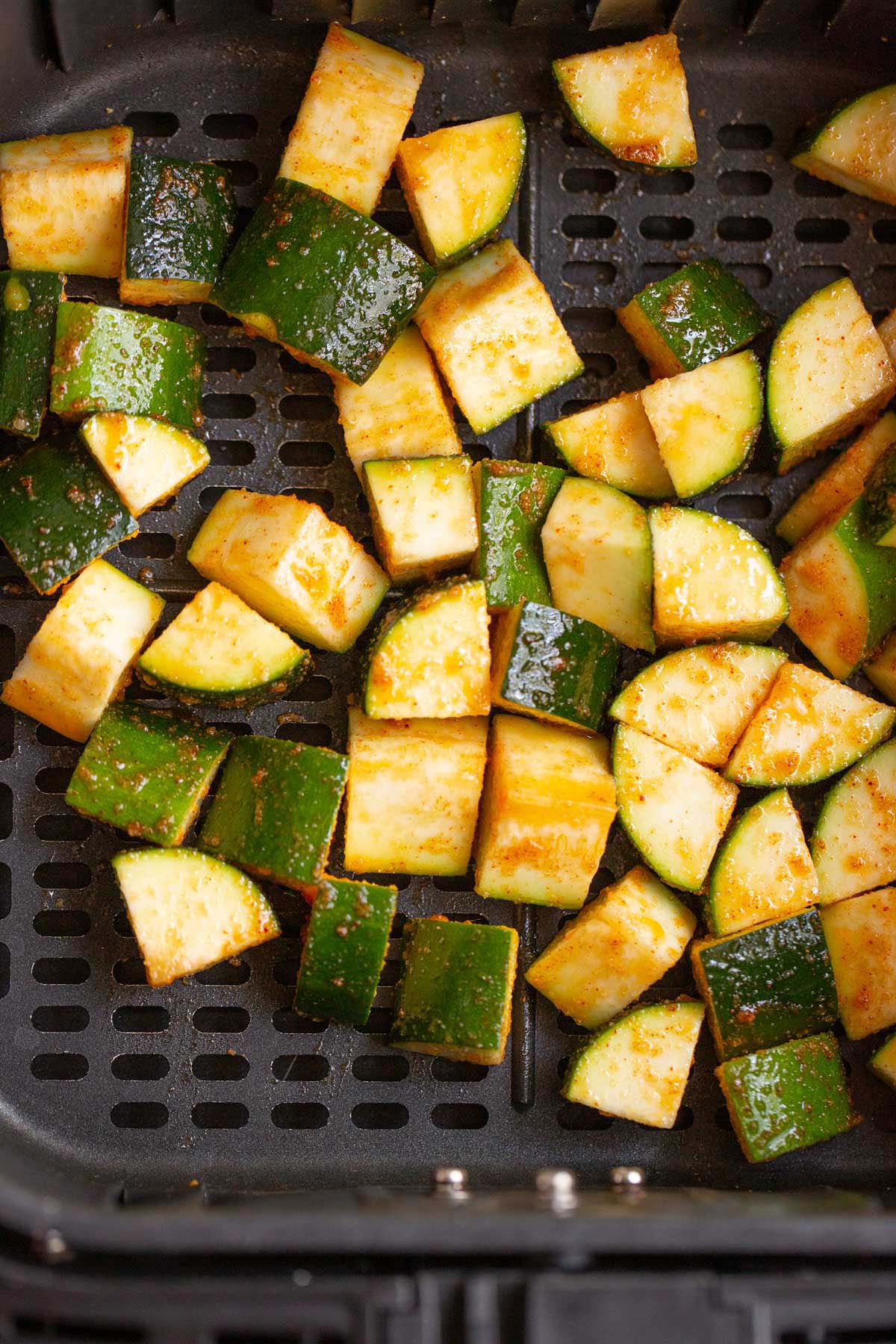 Unooked zucchini in air fryer basket