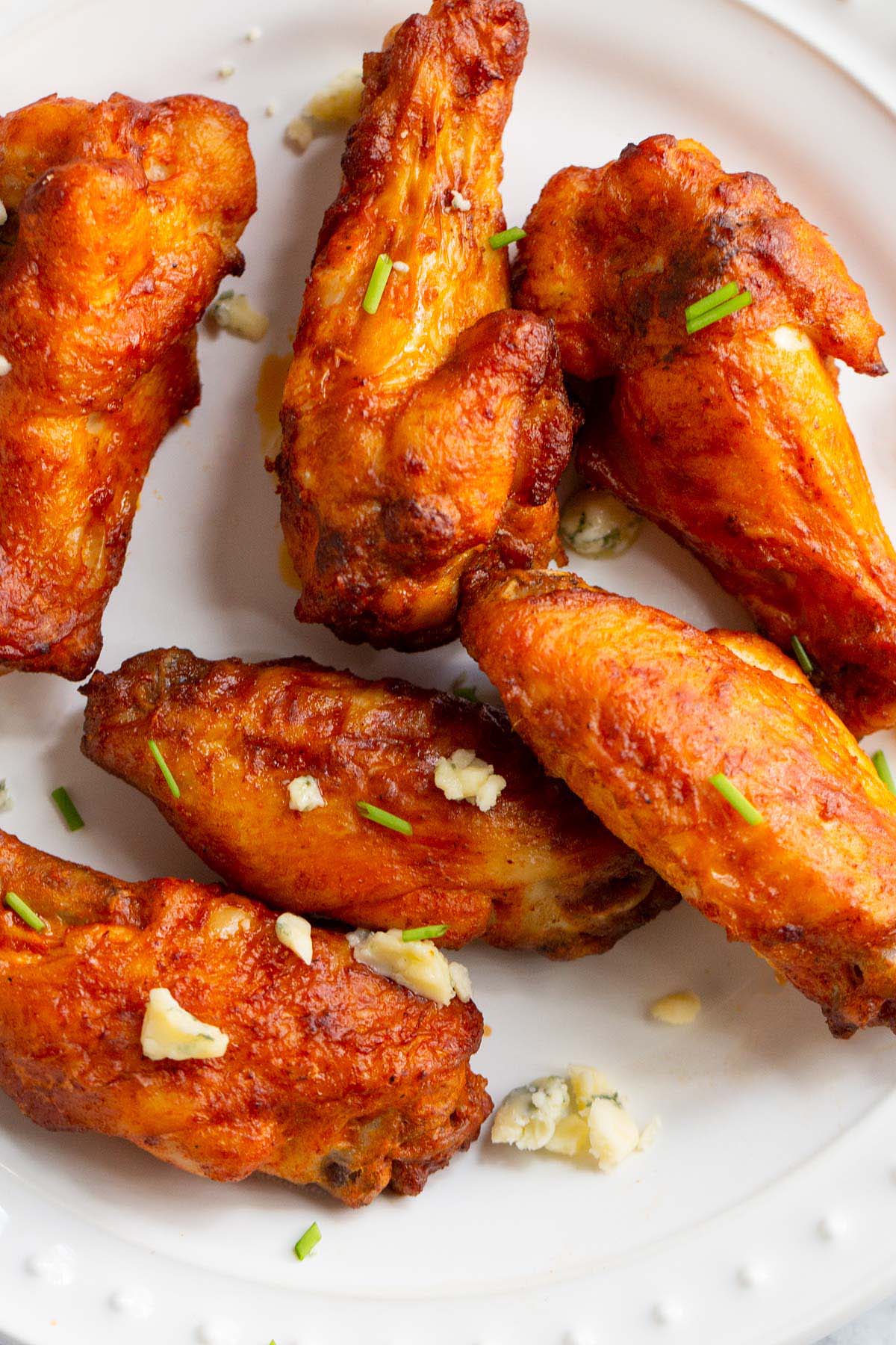 Buffalo wings on a plate with blue cheese crumbles.