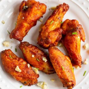 Buffalo wings on a plate with blue cheese crumbles.