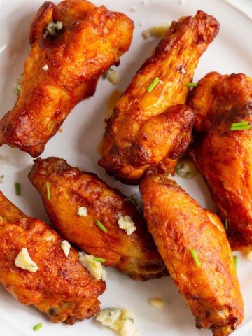 Buffalo wings on a plate with blue cheese crumbles.