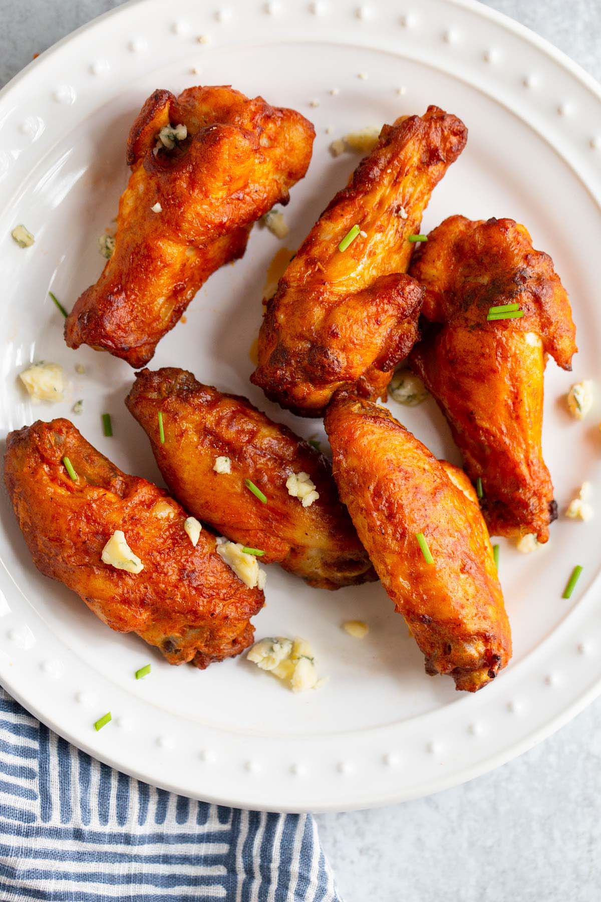 Buffalo wings on a plate with blue cheese crumbles.