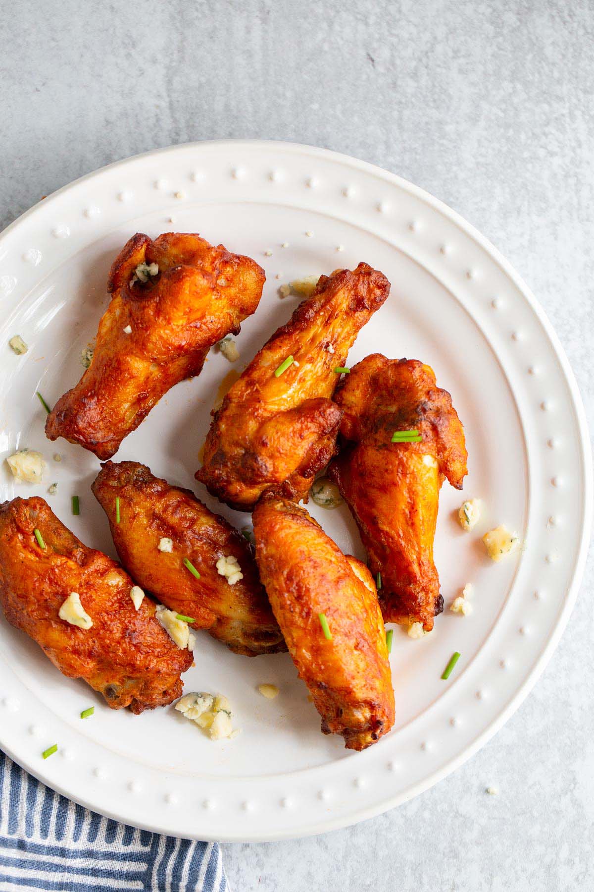 Buffalo wings on a plate with blue cheese crumbles.