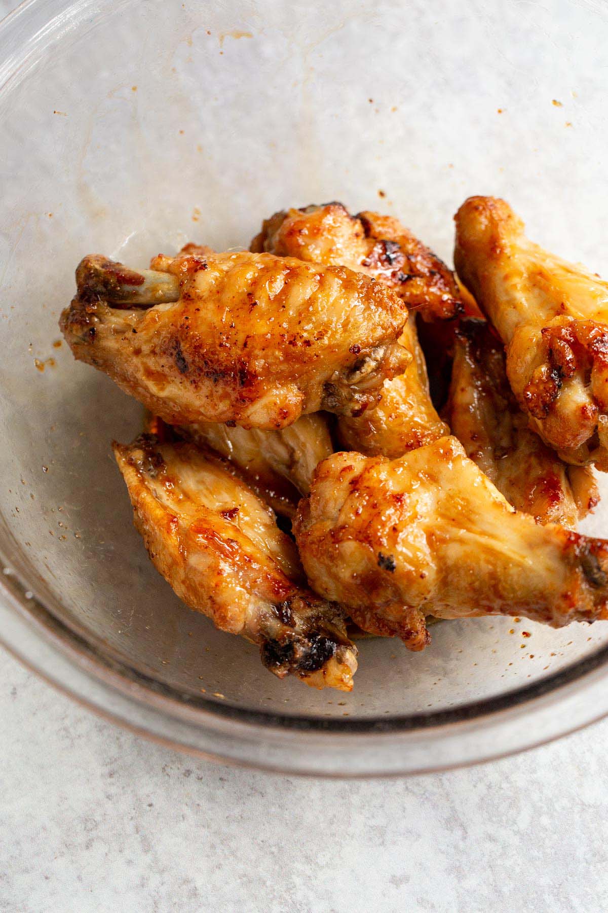 Chicken wings in a bowl tossed with honey garlic sauce.