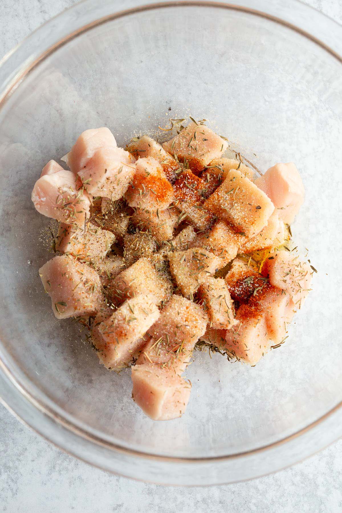 Raw cubed pork in a bowl with seasonings.