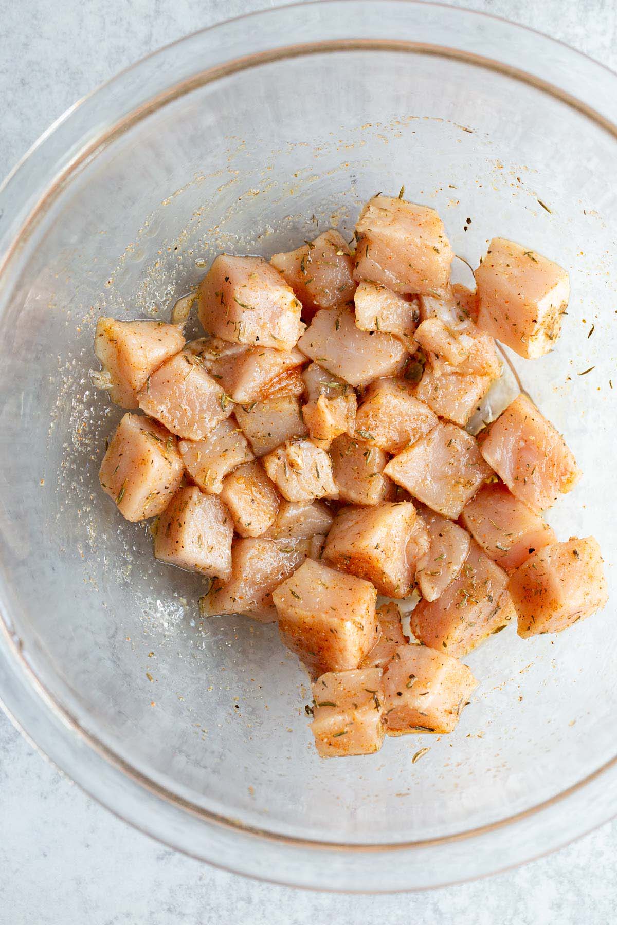 Raw cubed pork in a bowl mixed with seasonings.