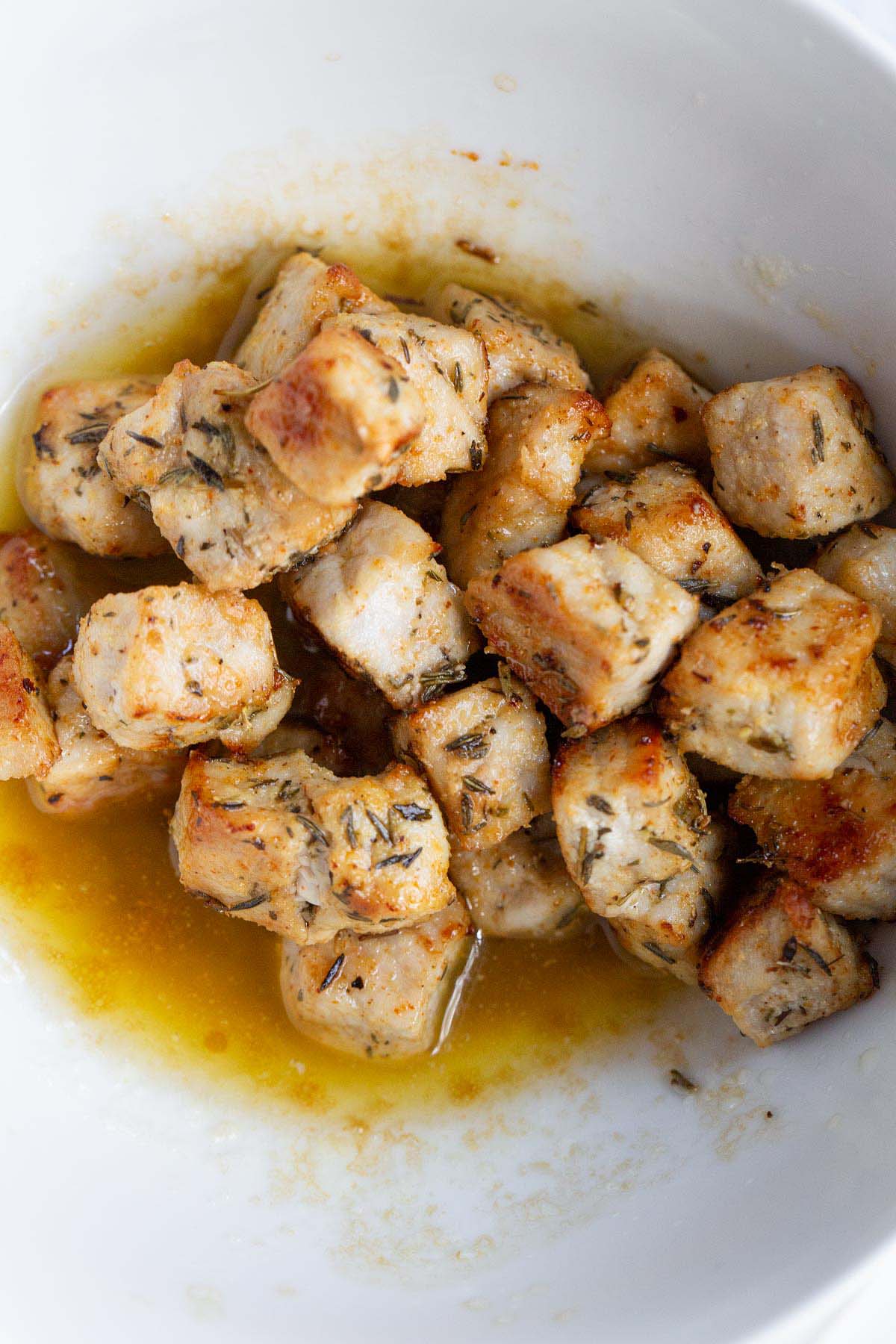 Pork chop bites in a bowl with butter sauce.