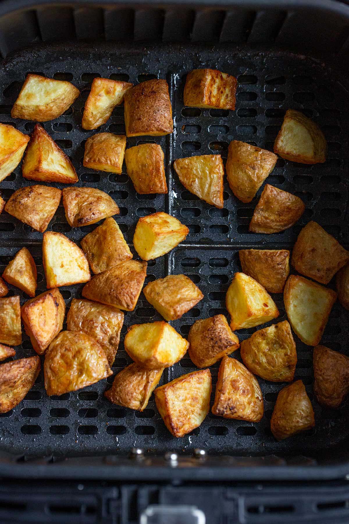 Air fried roasted potatoes in air fryer basket.