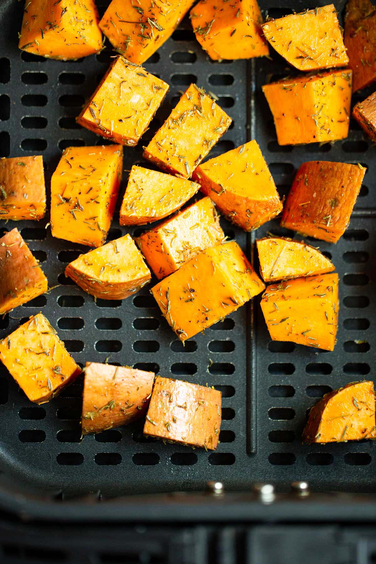 Uncooked sweet potato cubes in air fryer basket.