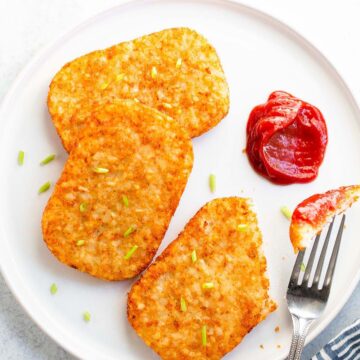 Hash brown patties with ketchup on a white plate.