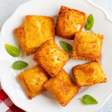 Air fried Trader Joe's breaded ravioli on a plate with basil leaves