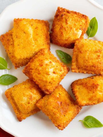 Air fried Trader Joe's breaded ravioli on a plate with basil leaves