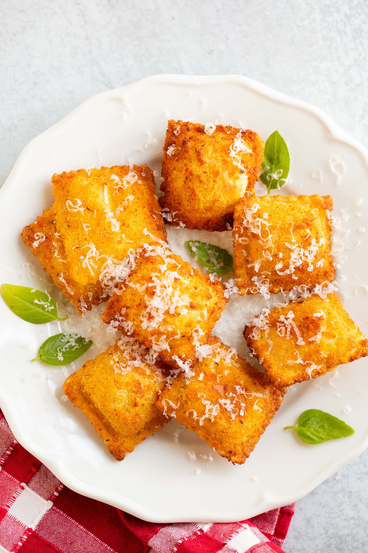 Air fried Trader Joe's breaded ravioli on a plate with basil leaves and parmesan