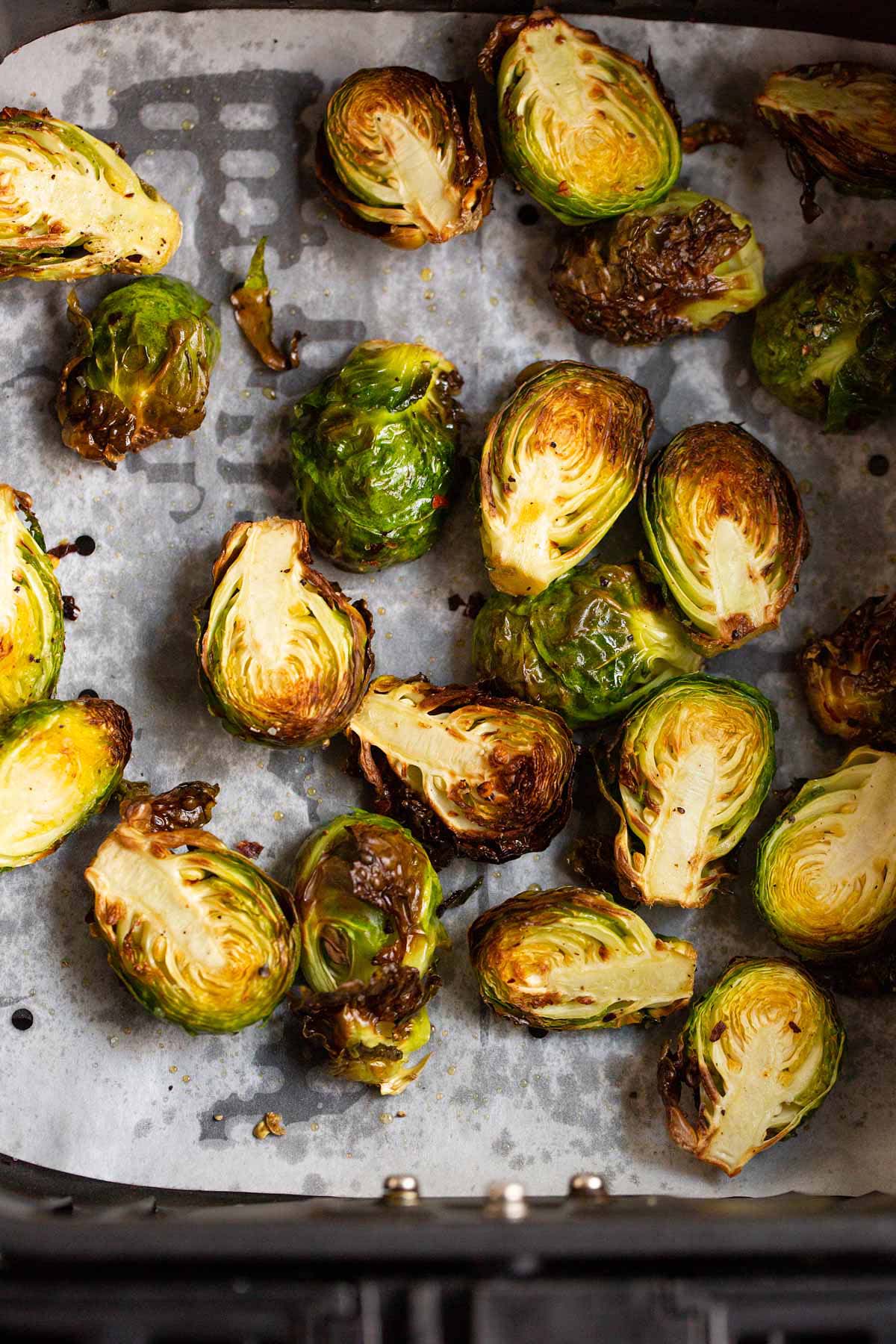 Cooked brussels sprouts in air fryer basket.