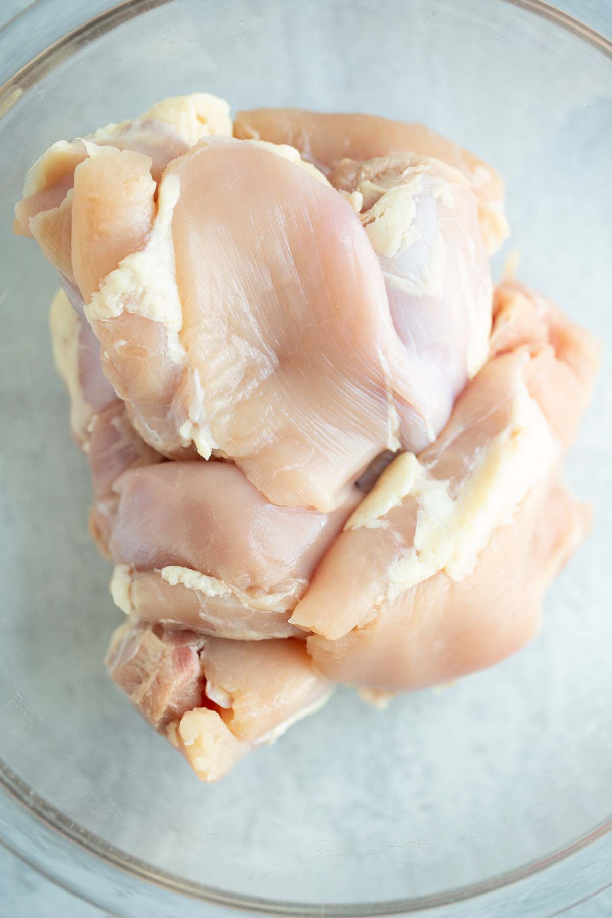 Raw chicken thighs in a large bowl.