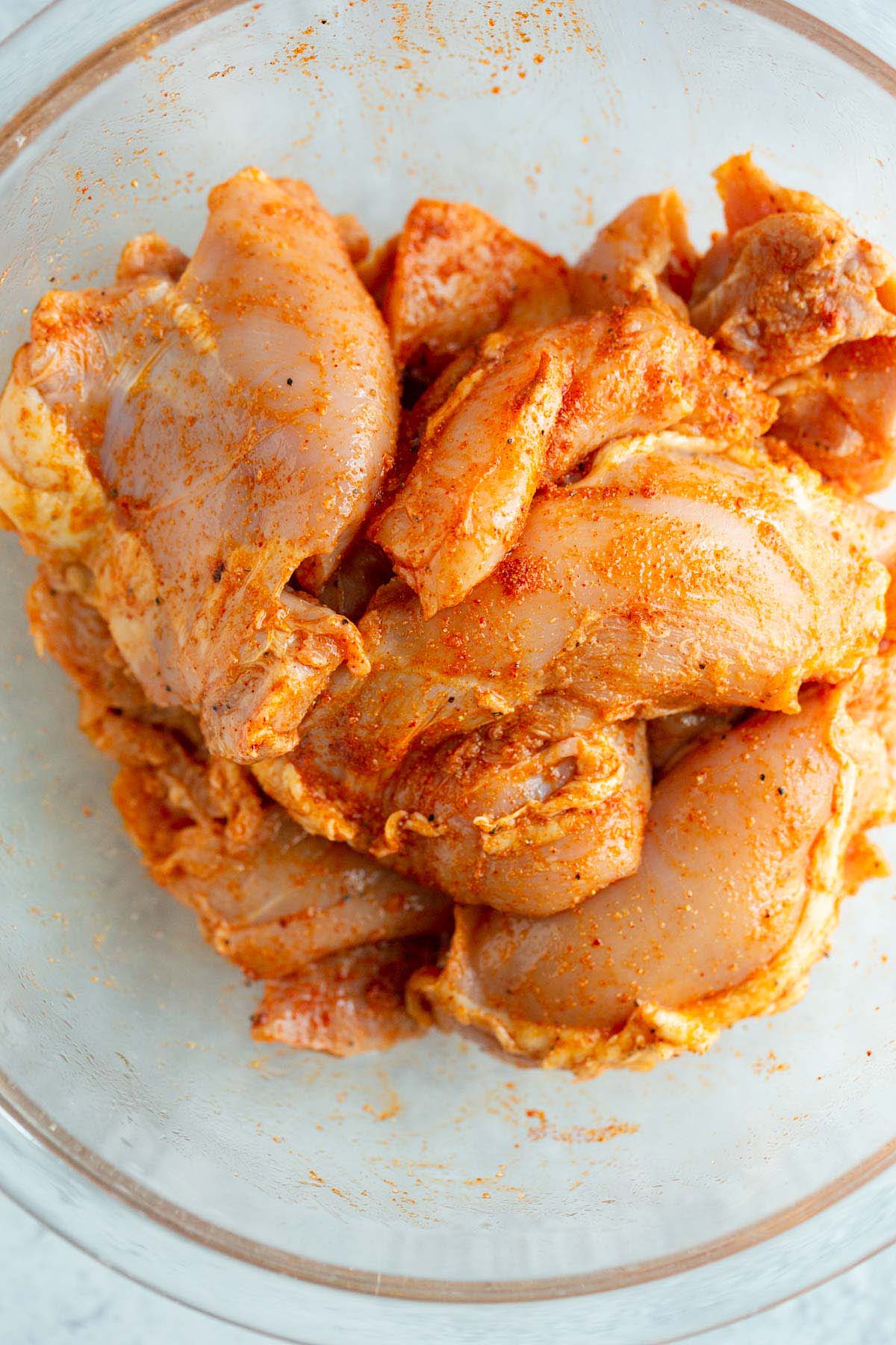 Uncooked chicken thighs in a bowl.