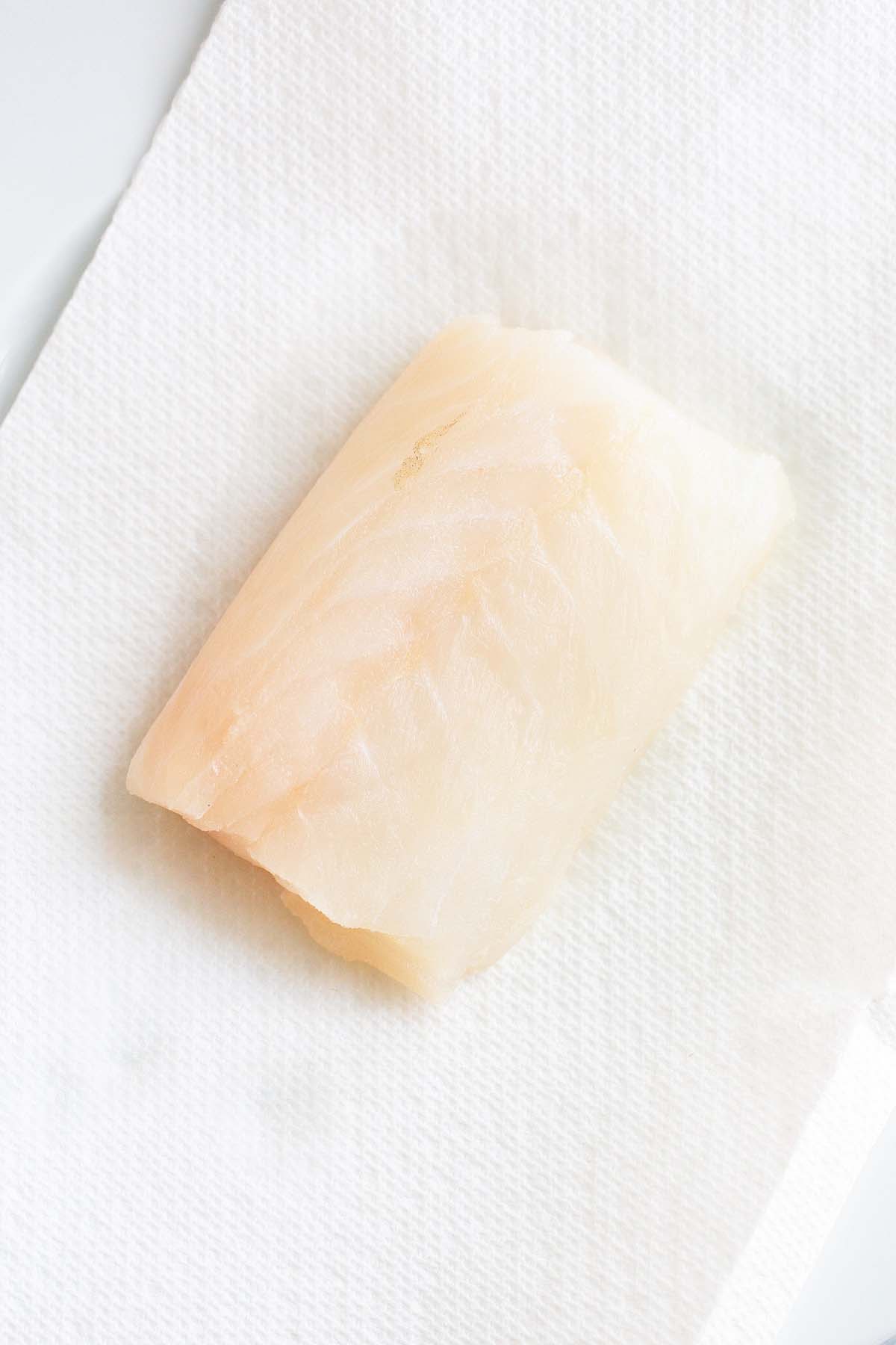 Raw cod fillet on paper towels.