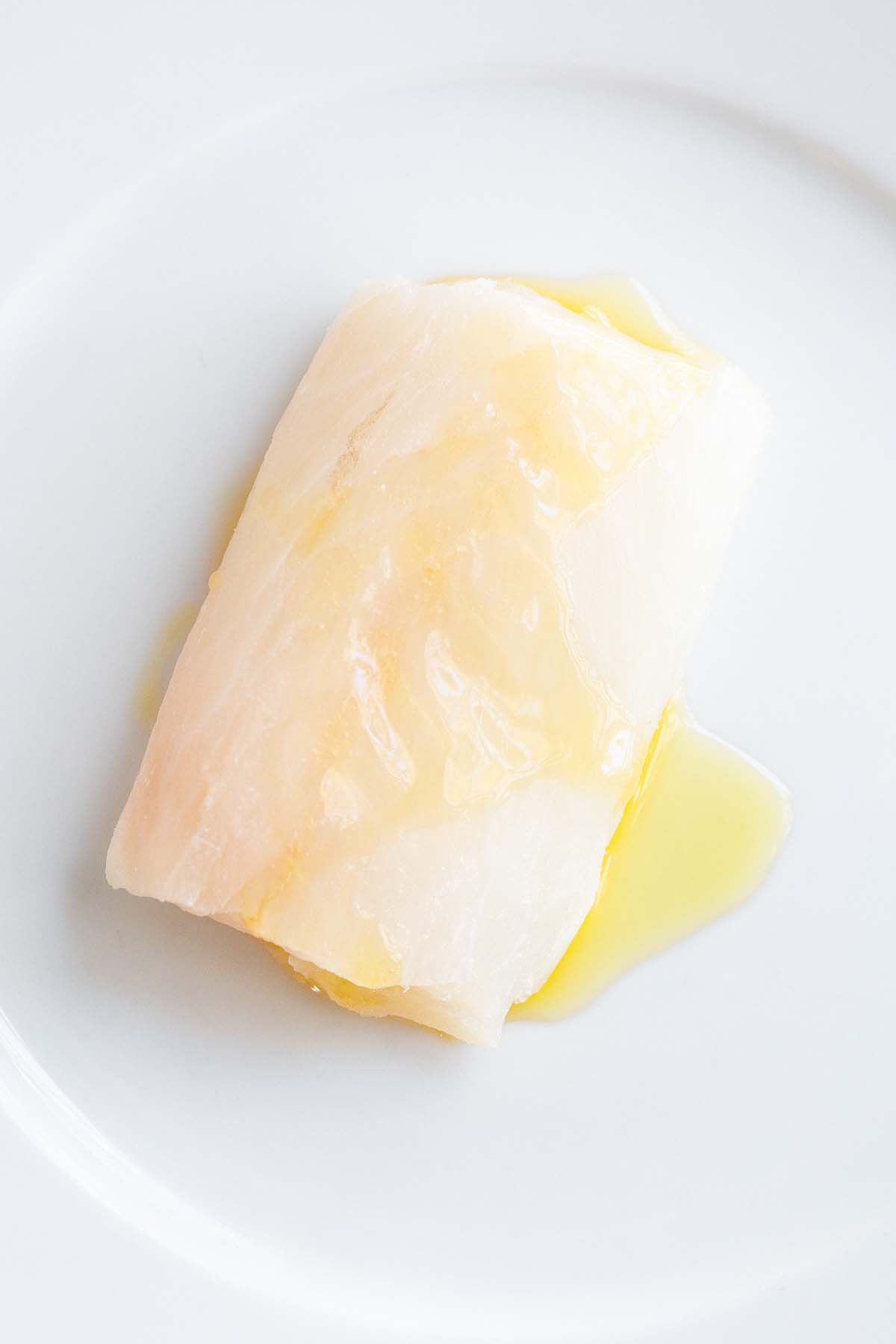 Raw cod fillet drizzled with olive oil.