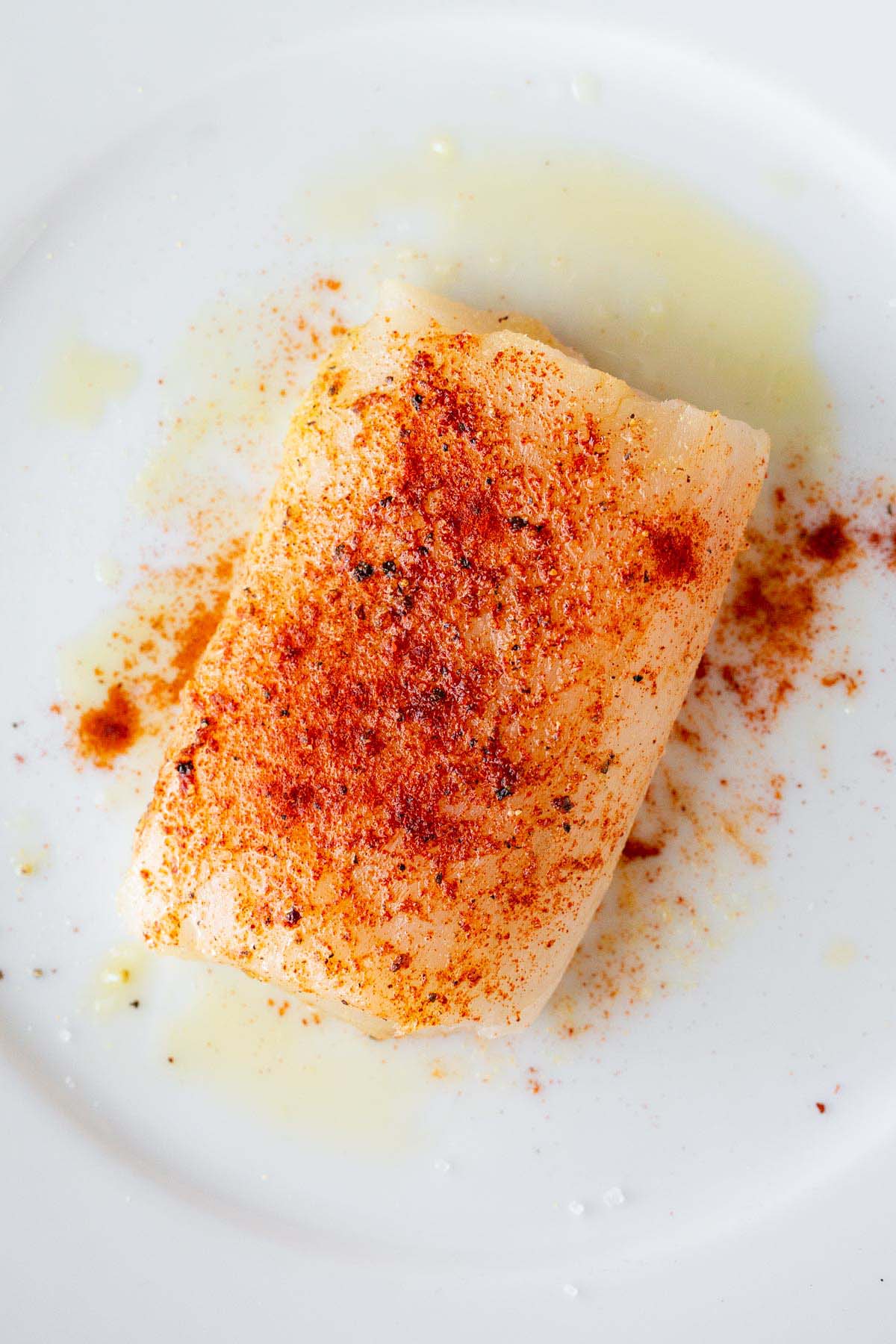 Raw cod on a plate with seasonings.