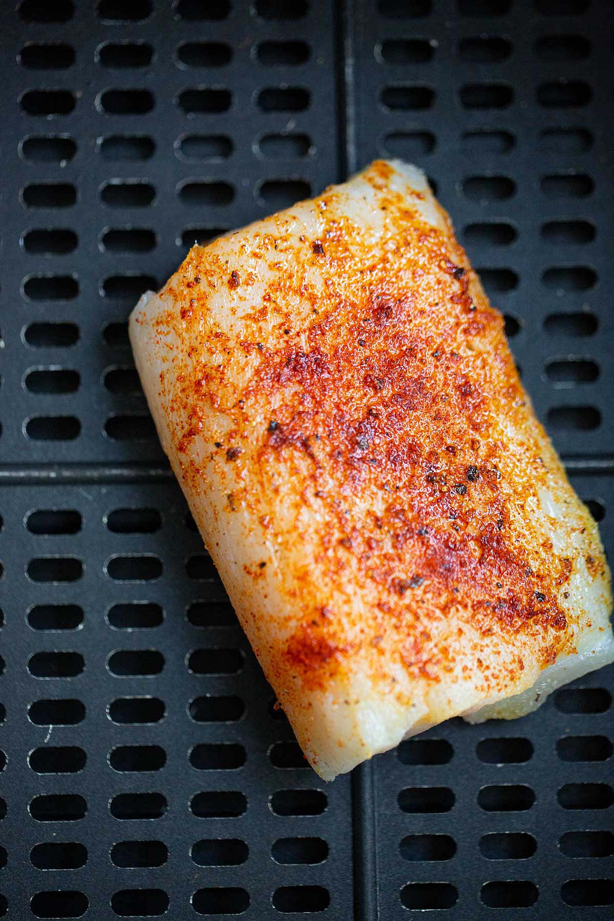 Uncooked air fryer cod in air fryer basket.