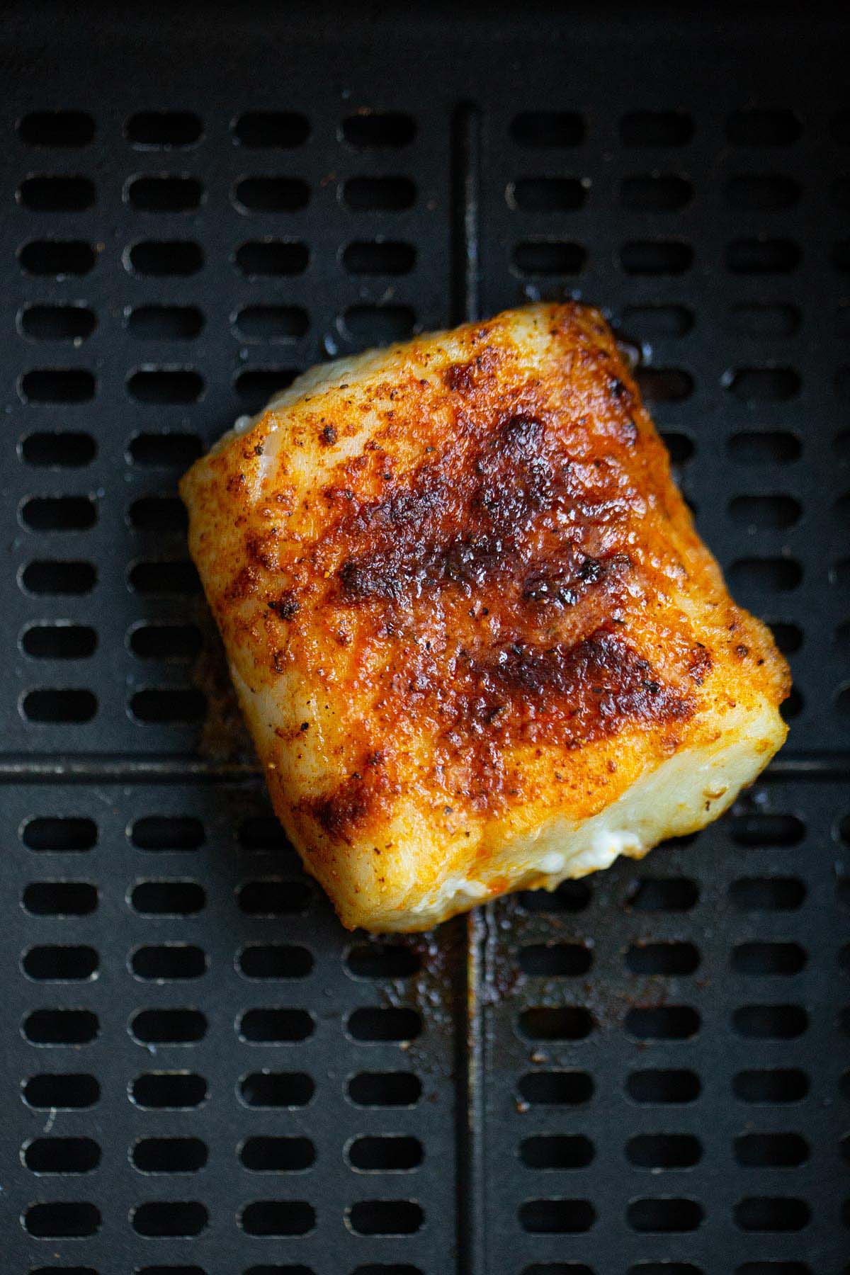 Air fried cod in air fryer basket.