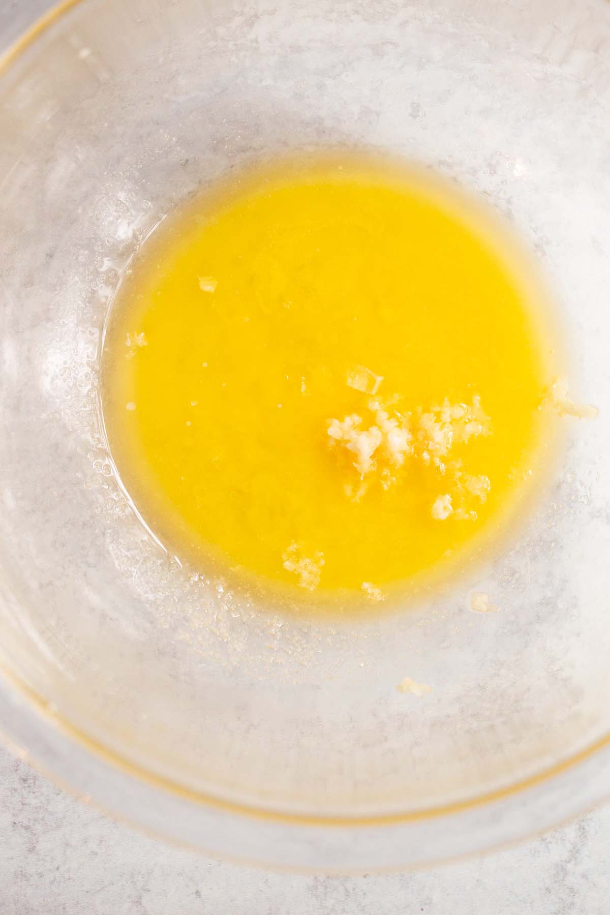 Melted butter, lemon juice, garlic, and salt in a glass bowl.