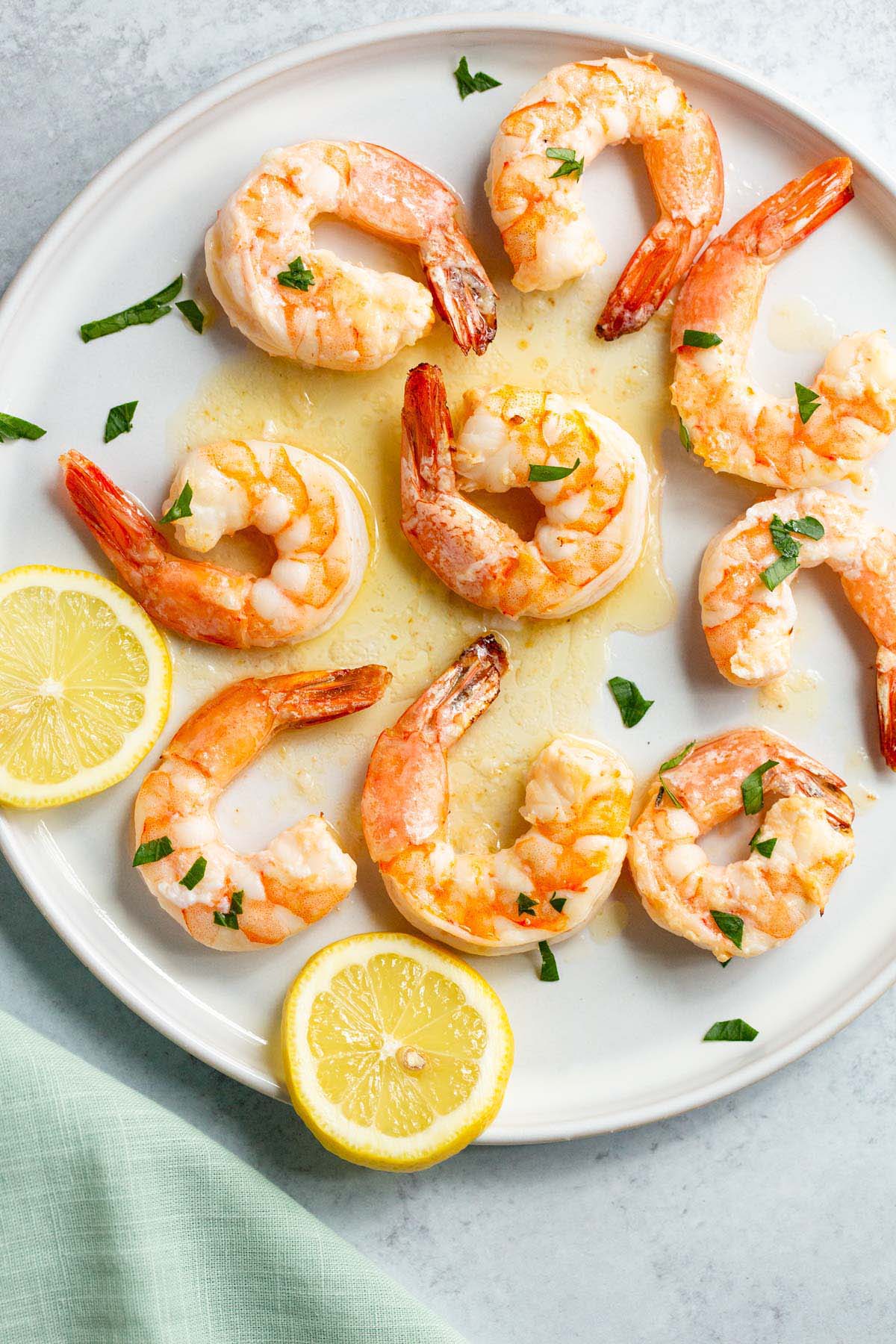 Garlic butter shrimp on a plate with lemons and fresh parsley.