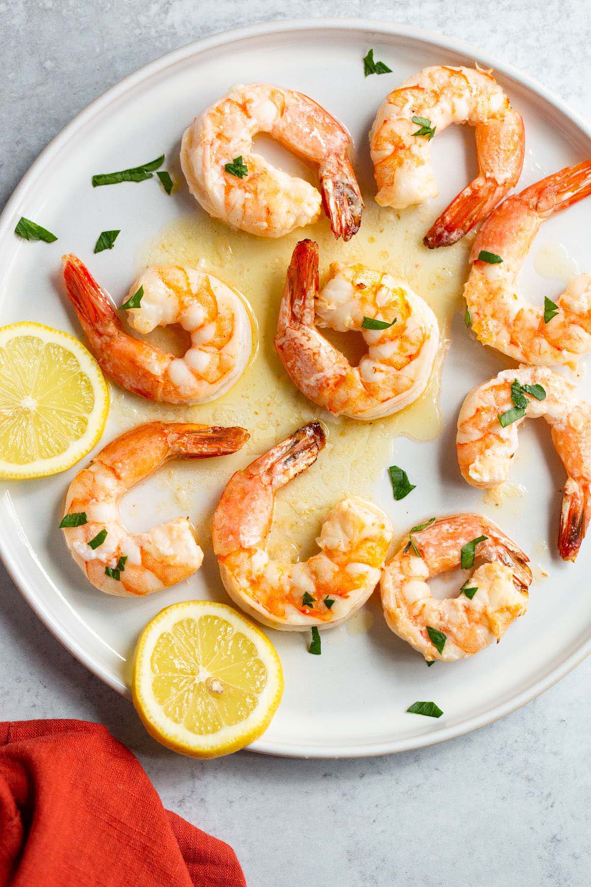 Garlic butter shrimp on a plate with lemons and fresh parsley.