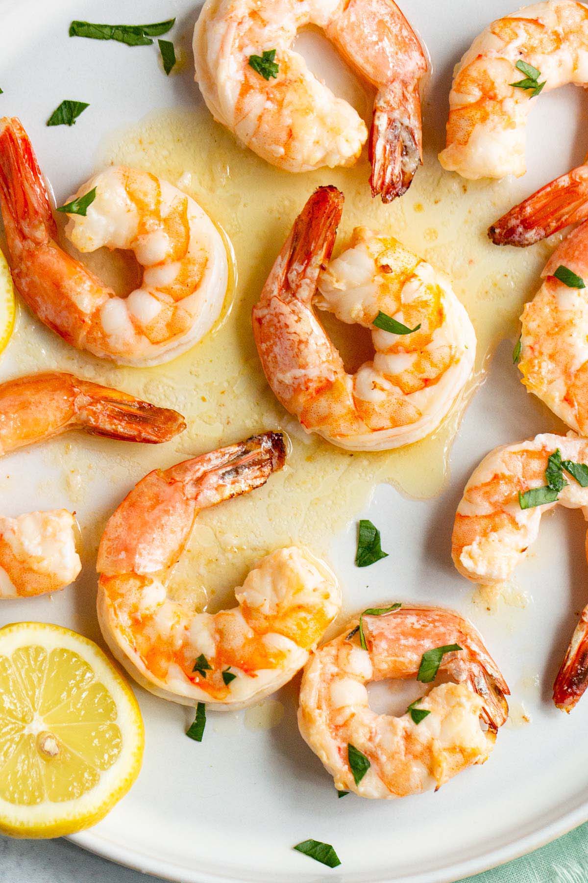 Garlic butter shrimp on a plate with lemons and fresh parsley.