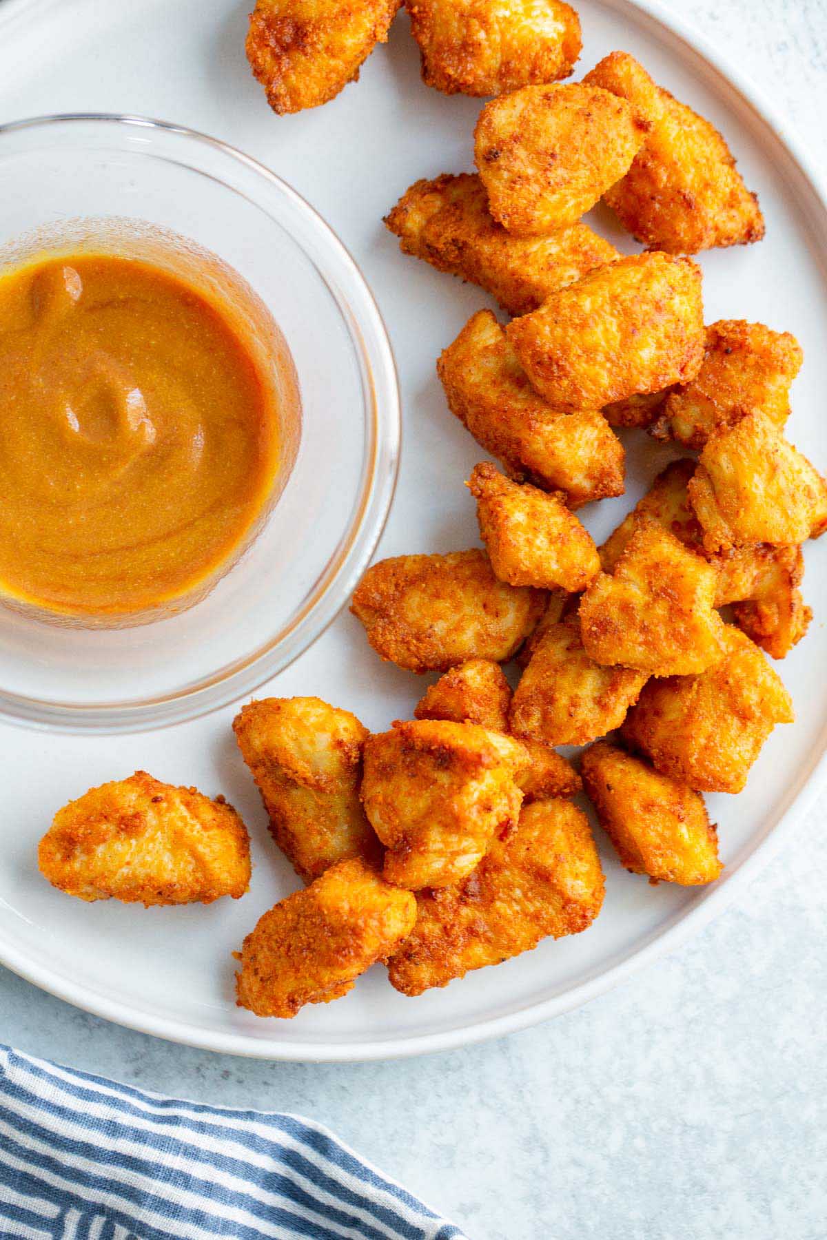 Air fried chicken bites on a plate with dipping sauce.