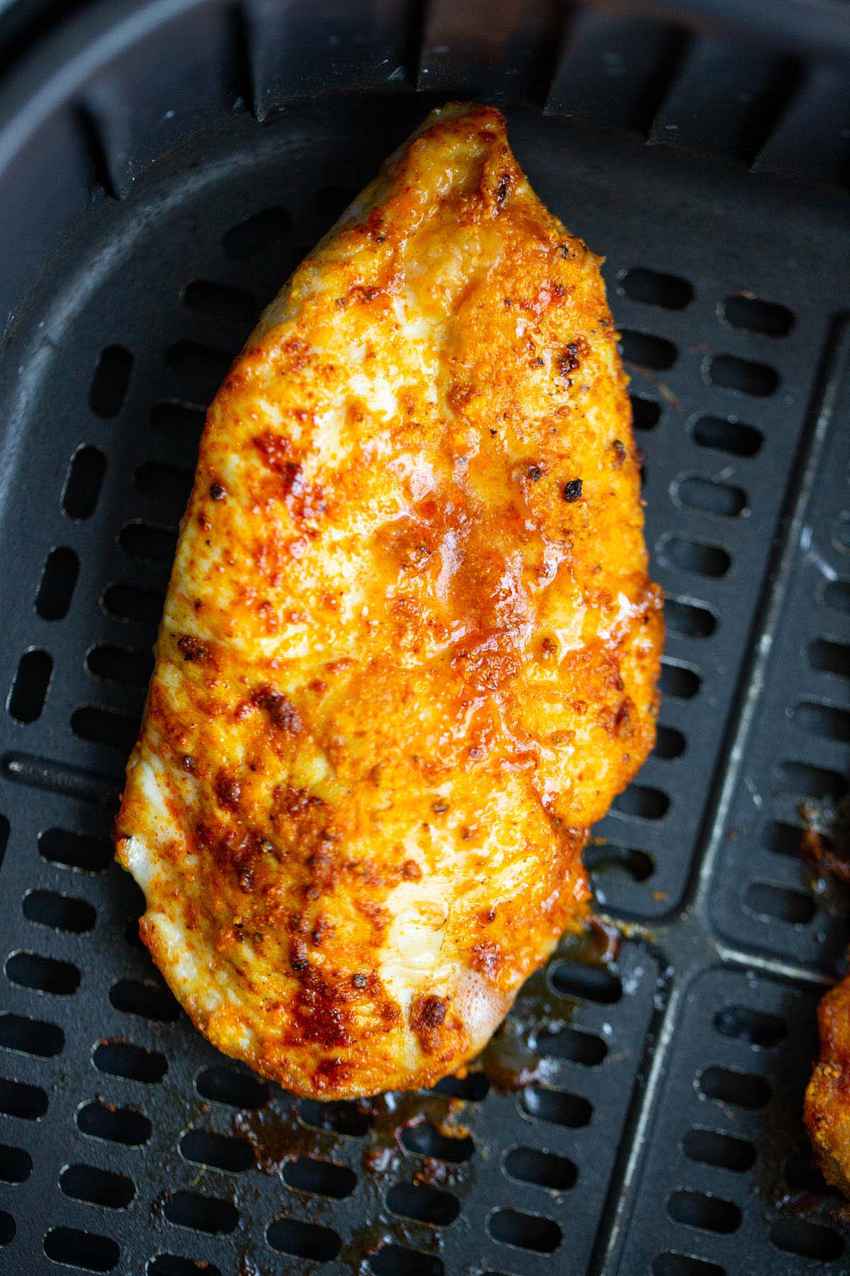 Air fried chicken breast in air fryer basket.