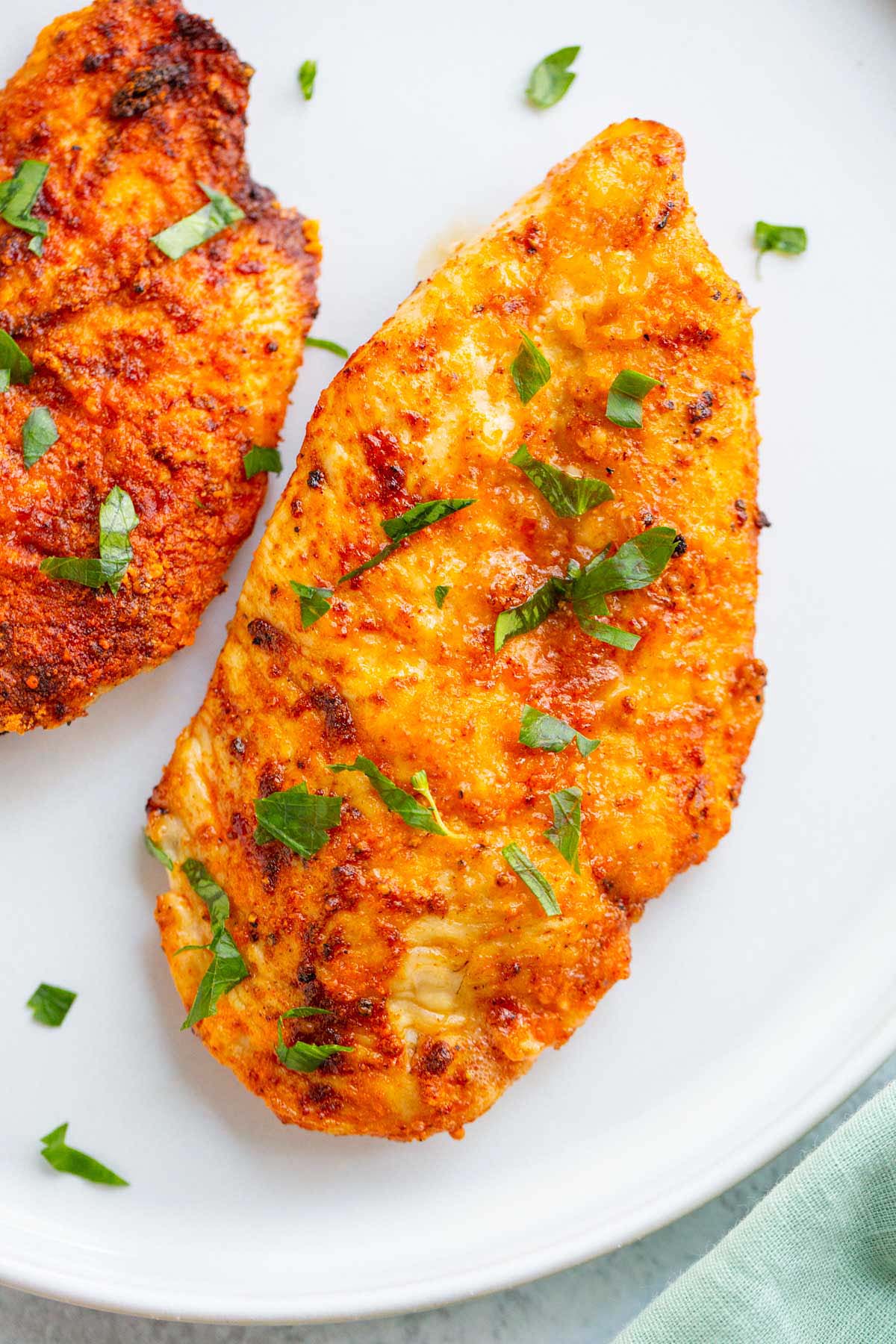 Air fried chicken breast on a white plate.