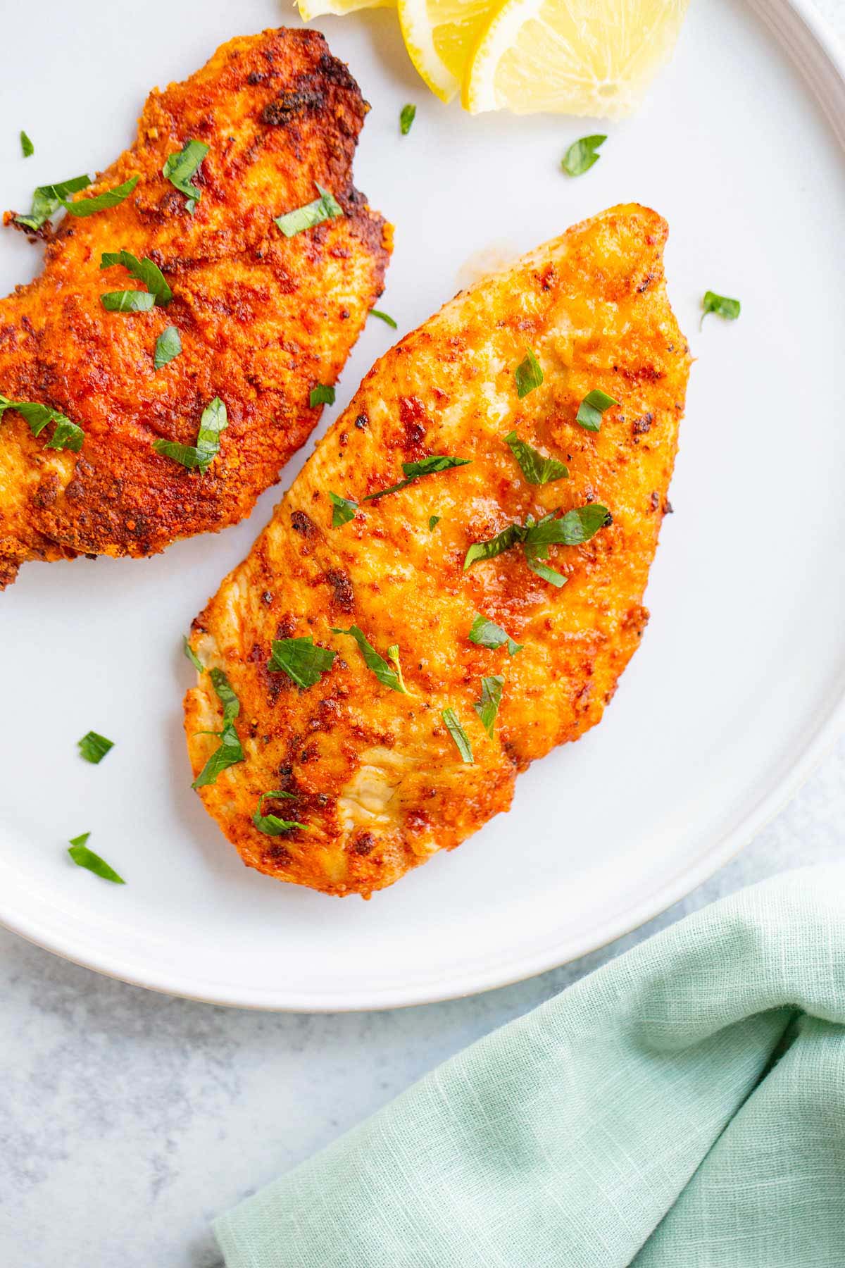 Air fried chicken breast on a white plate.