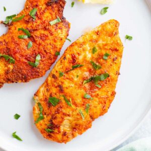 Air fried chicken breast on a white plate.