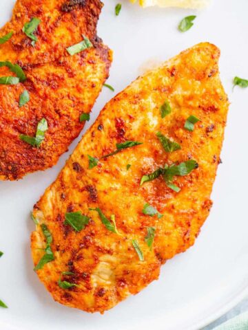 Air fried chicken breast on a white plate.