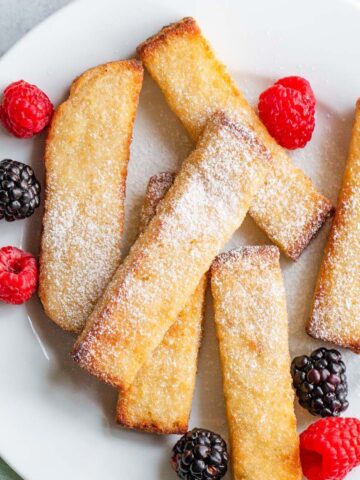 Air fried french toast sticks with berries and powdered sugar.