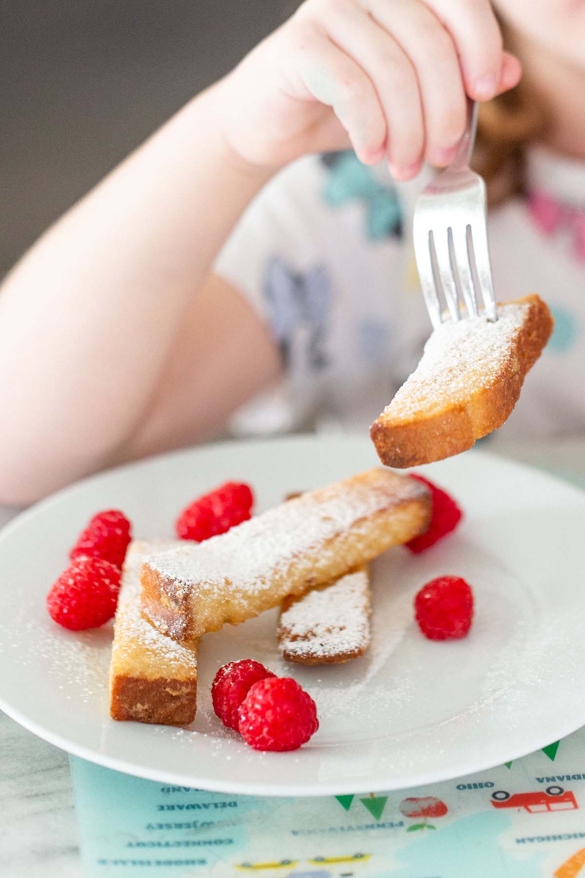 Kid eating french toast sticks.