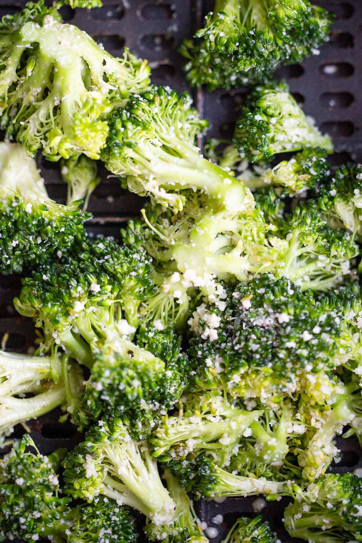 Raw broccoli in air fryer basket.