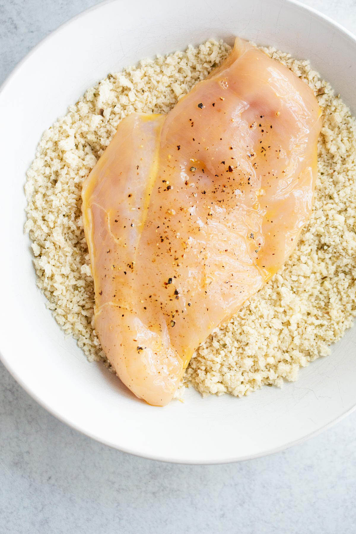 Dipping chicken breast in panko and parmesan.