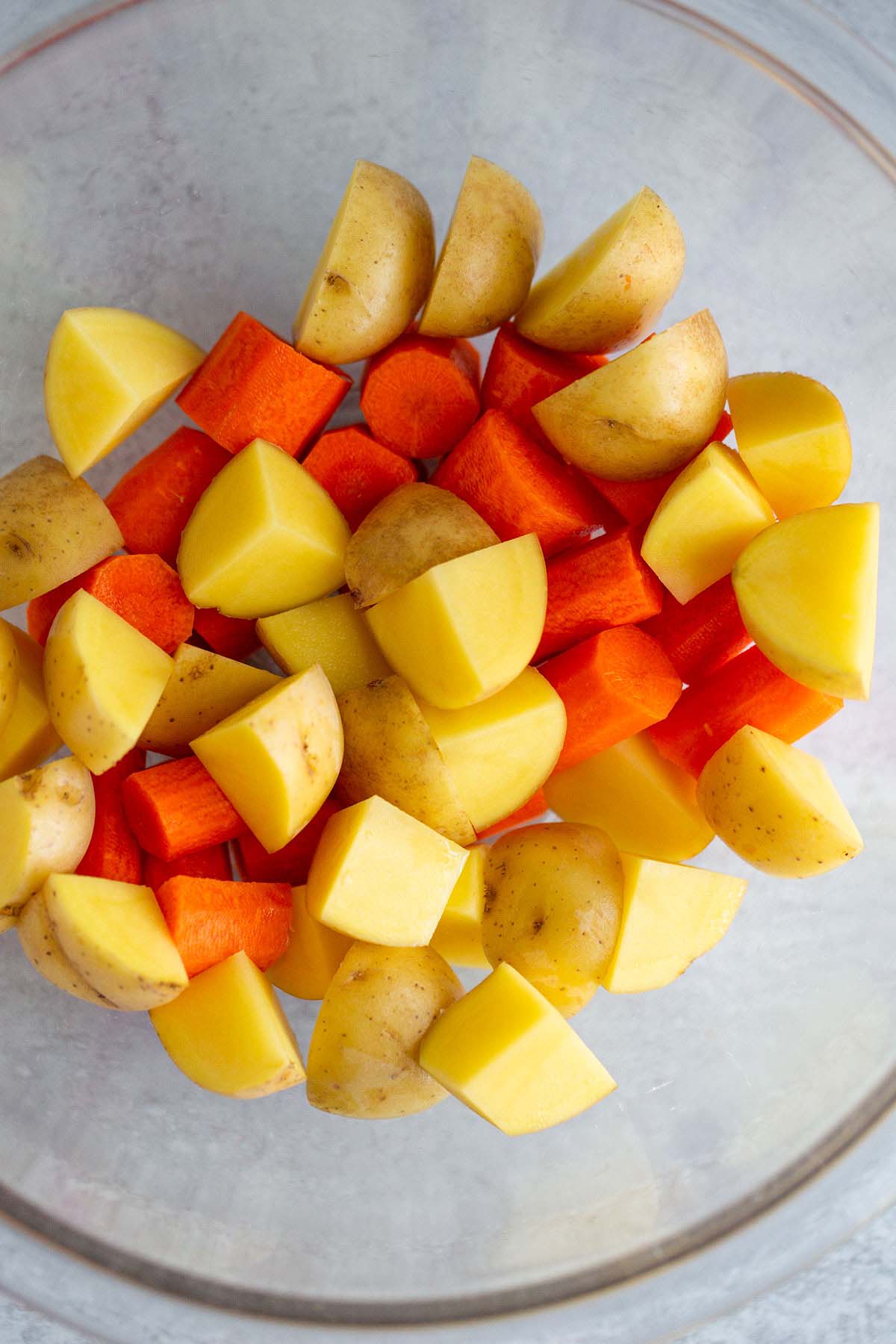 Raw potatoes and carrots in a bowl.