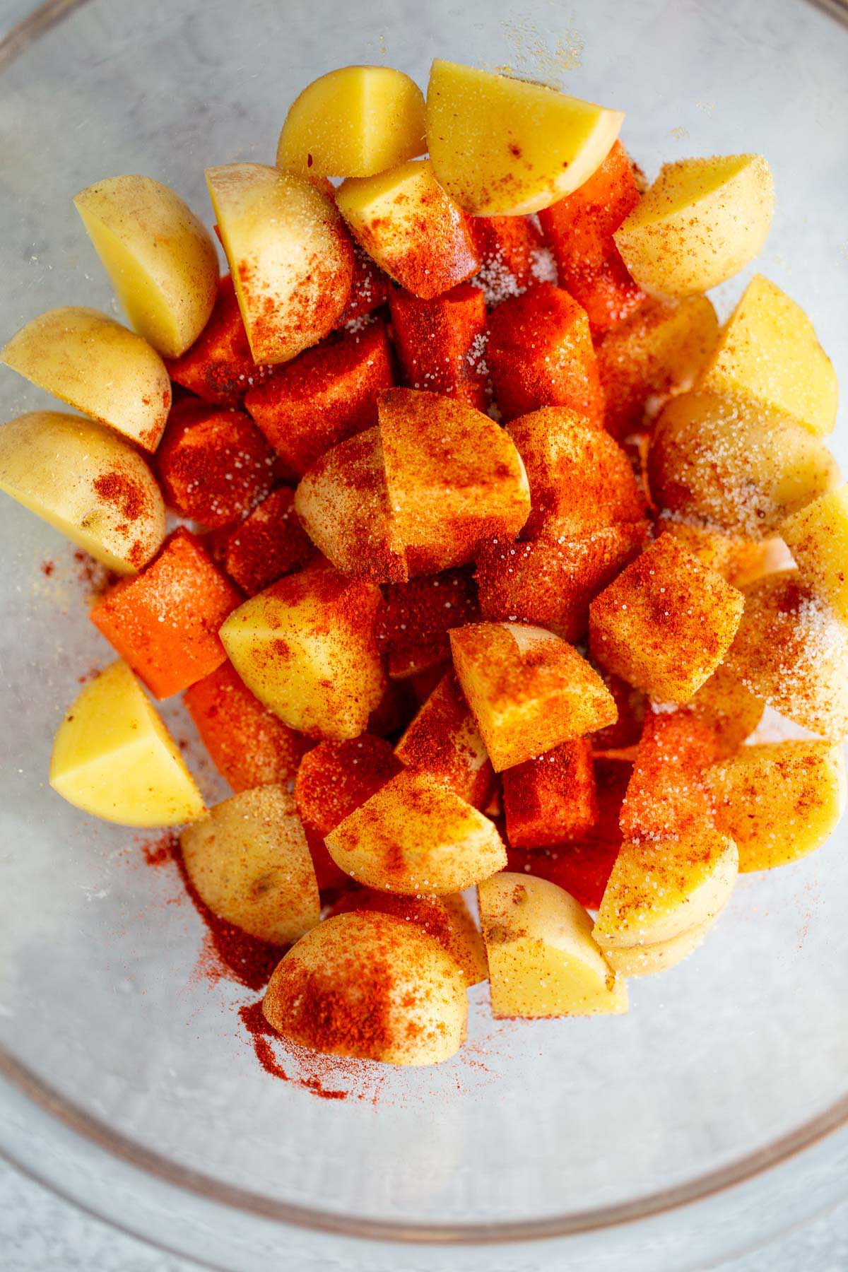 Potatoes and carrots sprinkled with seasonings.