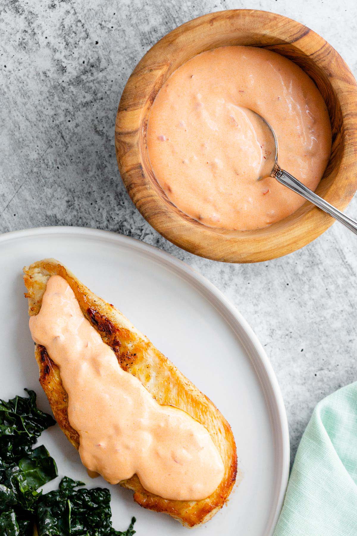 Calabrian mayo in a bowl with some spooned over a chicken breast.