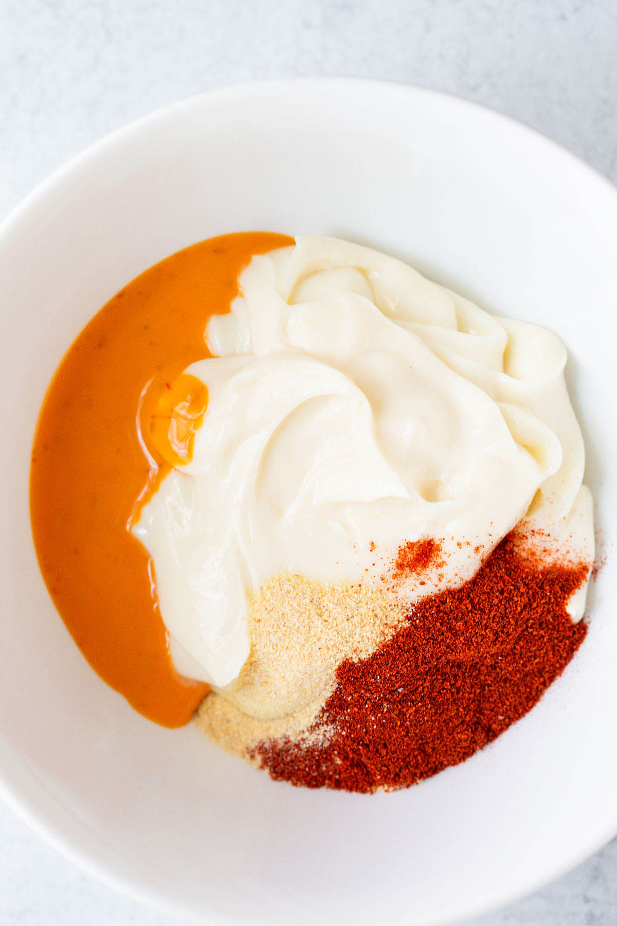 Peri peri mayo ingredients in a white bowl.